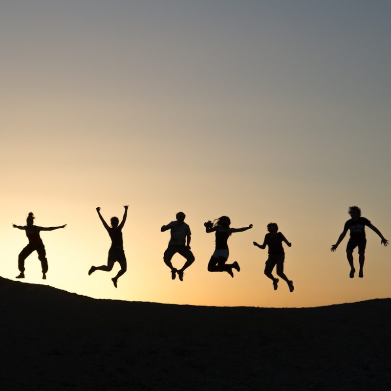 six silhouette of people jumping during sunrise